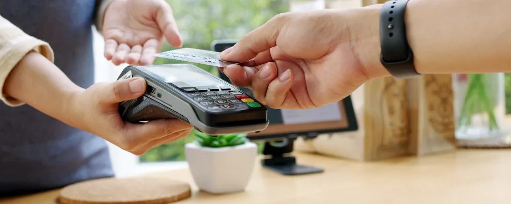 Customer scanning credit card at a payment terminal that will charge credit card processing fees.