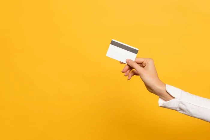 a hand holding out a credit card that can be input on a virtual terminal against an orange background
