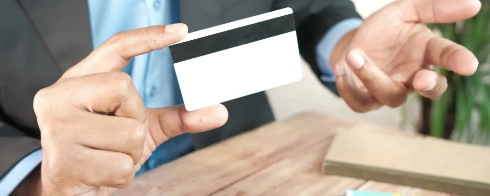 A hand holding a Visa credit card that he acquired as part of the company's monitoring program.