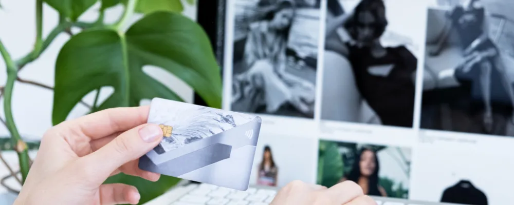 A person holding a credit card in front of a computer screen, deciding how to protect their business from identity theft.