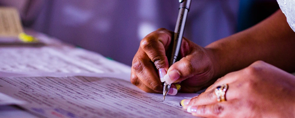A woman signing a piece of paperwork that relates to laws and regulations in the world of payment processing.