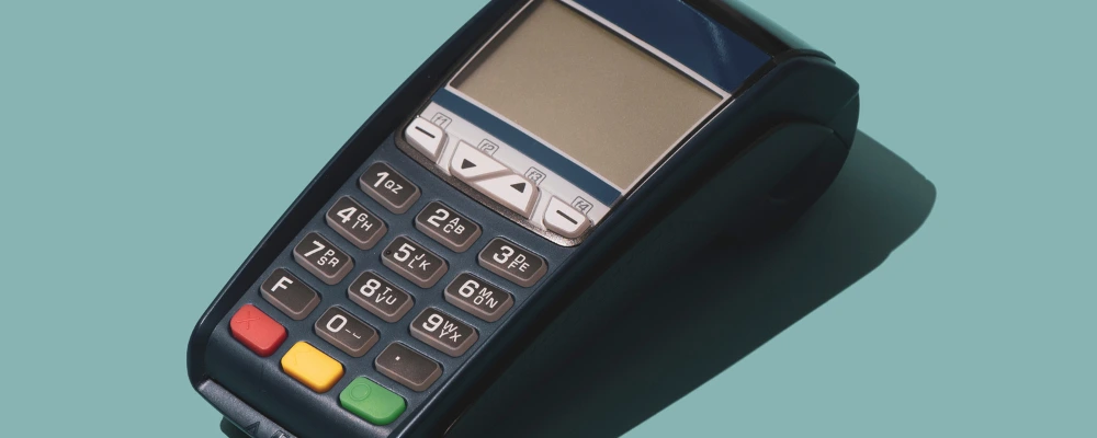 A payment terminal with keypad on green backdrop—used with merchant services or payment processors.