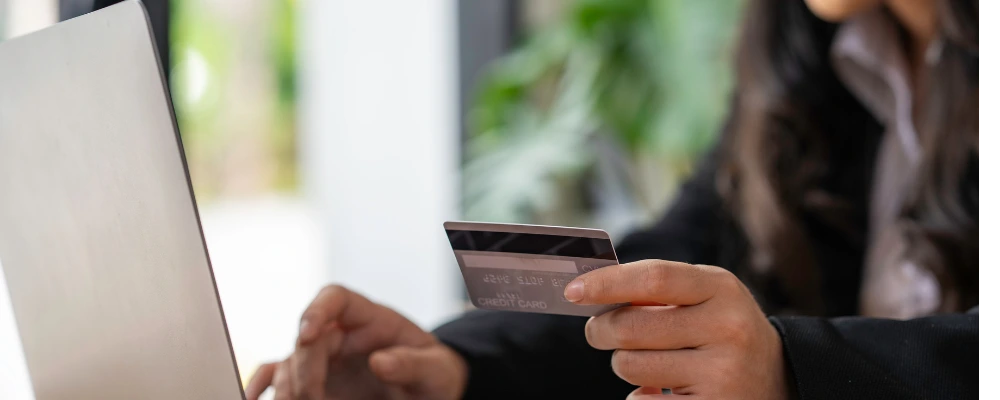 A woman researching payment gateway fees and pricing while simultaneously expediting a purchase with her credit card.