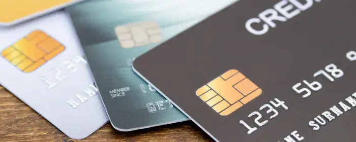 a black EMV chip credit card on top of a blue and a purple credit card that are processed using tiered pricing