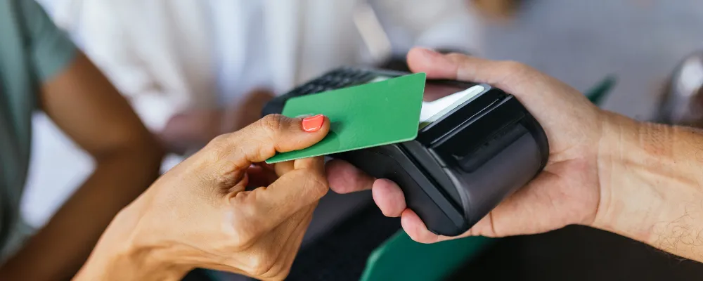 A hand holding a green card that will be used with a compatible point of sale system.