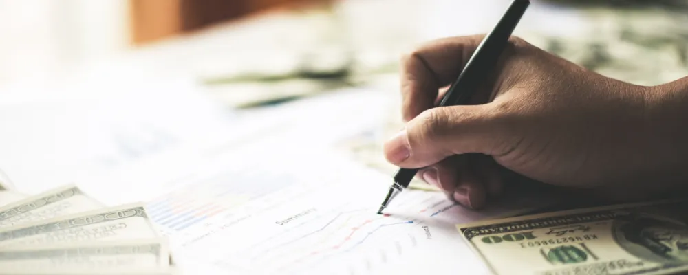 A hand signing a piece of financial paper specifically relates to an ISO and the payment processing procedure.