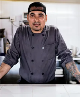 Man standing in the kitchen at his restaurant.