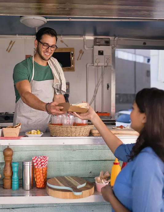 A merchant in an apron at a food truck.