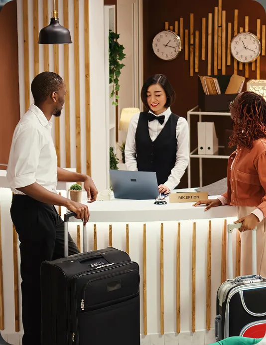 Hospitality worker checking two guests in.