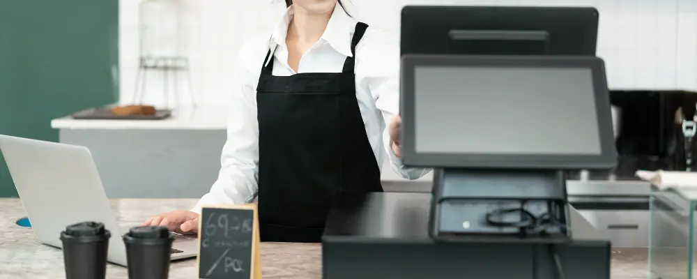 A merchant using an all-in-one POS system at a retail counter.